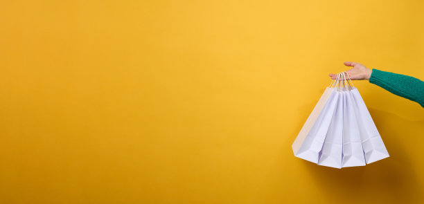 女性手拿着一次性纸袋，袋子上有提手，用来装食品和衣服。可回收的包装。“零浪费”。出售横幅图片下载