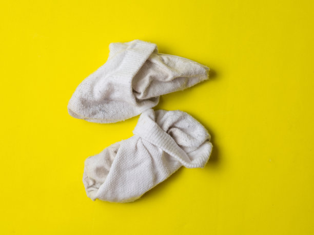 黄色背景上皱巴巴的白色脏袜子图片下载