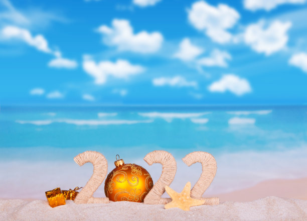 2022年有黄色圣诞球、礼物和海星在沙滩上图片下载