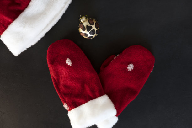 圣诞老人红色温暖手套，圣诞老人的帽子和老虎装饰装饰物在黑色的背景。象征2022年新年是老虎。前视图。图片下载