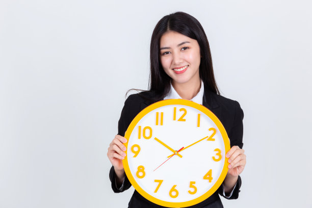 漂亮年轻的亚洲女商人感觉幸福和微笑的手显示闹钟和指向，肖像积极成功自信的美丽年轻女性。图片下载
