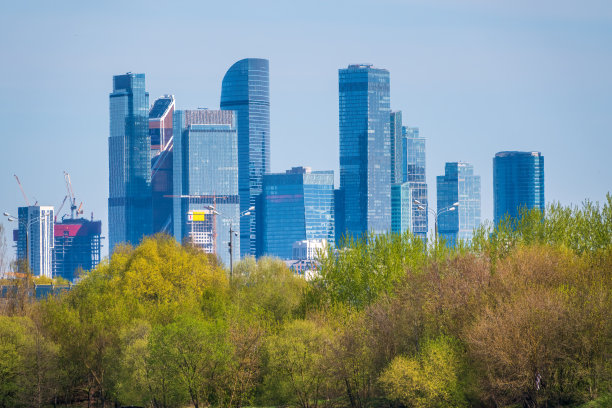 绿树背景在莫斯科现代摩天大楼。图片下载