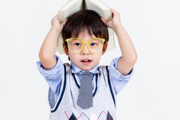 小男孩戴着眼镜，带着白色背景的书，教育理念。图片下载