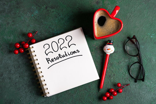 摆在桌上的2022年新年决心。2022年新年决心，绿色背景，咖啡杯，笔记本和圣诞装饰。新年目标、计划、决心、经营理念图片下载