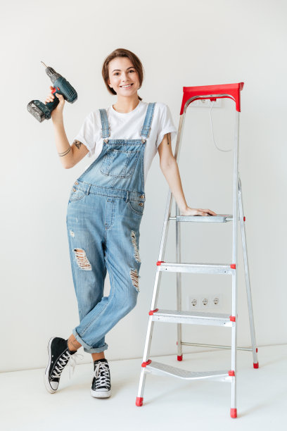 微笑的女人拿着钻头倚在梯子上图片下载
