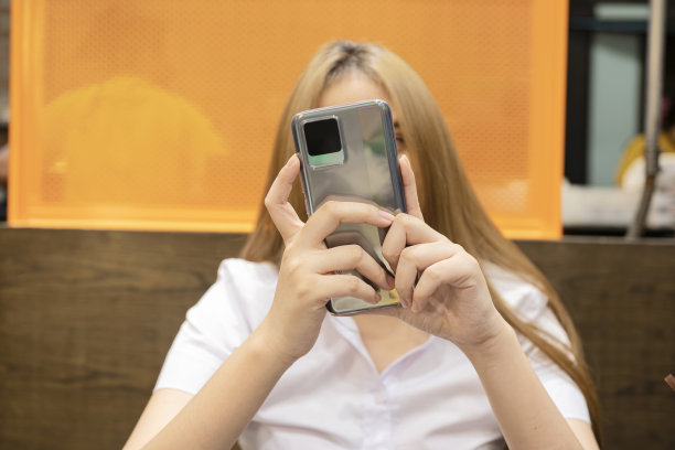 年轻的潮女坐在舒适的室内，使用现代智能手机设备的特写图像图片下载