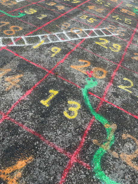 全帧图像沥青操场表面涂有蛇和梯子游戏，一排排的方块和数字，高架的看法图片下载
