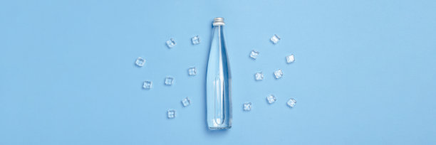 玻璃瓶与清澈的水在蓝色的背景和冰块。健康美观念，水平衡，渴，热，夏。平铺，俯视图。横幅图片下载