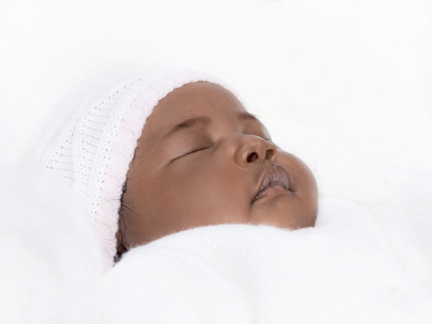 可爱的一个月大的女婴睡在她的床上，白色和粉红色的婴儿衣服，照片，白色的背景图片下载