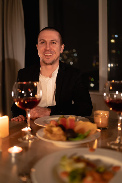 情人节晚餐，一个男人在节日餐桌上用红酒和蜡烛，浪漫的家庭约会，男人为女朋友准备了一个惊喜图片下载