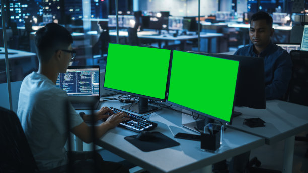 夜班办公室:正在操作绿屏色度键台式电脑的年轻日本男子。程序员团队，编写代码，创建现代软件，电子商务应用程序设计，电子商务编程图片下载