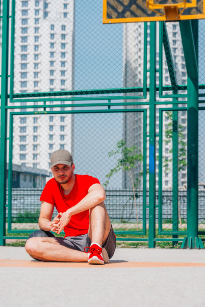 两名篮球运动员在一场令人筋疲力尽的篮球赛后坐在球场上休息。图片下载