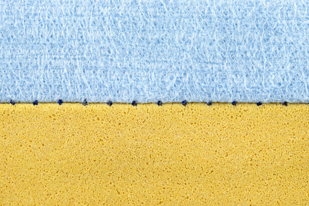 背景是一张用于清洗玻璃和盘子的蓝色和黄色海绵的微距照片，接缝是可见的。图片下载