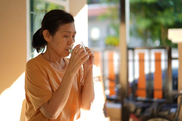 年长的亚洲妇女早上在家里喝水。图片下载