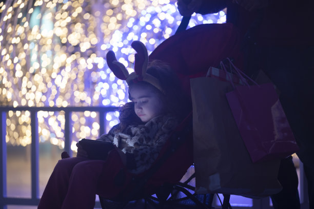 照片的女孩穿着服装驯鹿鹿角在圣诞灯前图片下载