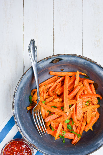 近距离的自制红薯片在古老的古董碗，银叉子和辣椒酱在白色的木制桌子上。从以上观点。垂直的照片。图片下载