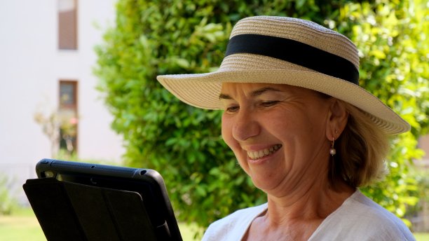 戴帽子的年长金发女商人在自己的绿色花园中使用平板电脑、数字平板电脑进行商务工作或学习。50 - 55岁的女人。自己的经营理念和培训，在线课程为老年人提供年长培训图片下载