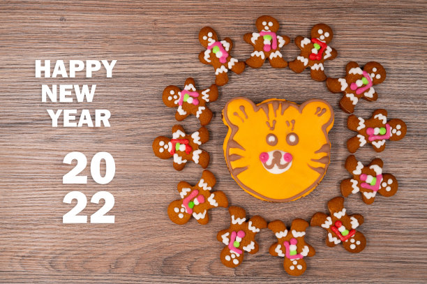 在木桌上放上釉的姜饼人，周围是老虎形状的橙色姜饼饼。2022年新概念。图片下载