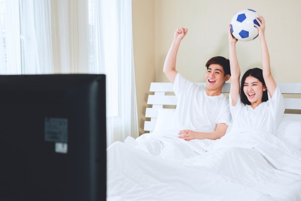 十几岁的夫妇躺在家里看电视电视体育足球足球比赛庆祝胜利的进球。图片下载