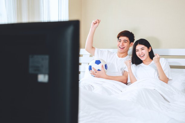 十几岁的夫妇躺在家里看电视电视体育足球足球比赛庆祝胜利的进球。图片下载