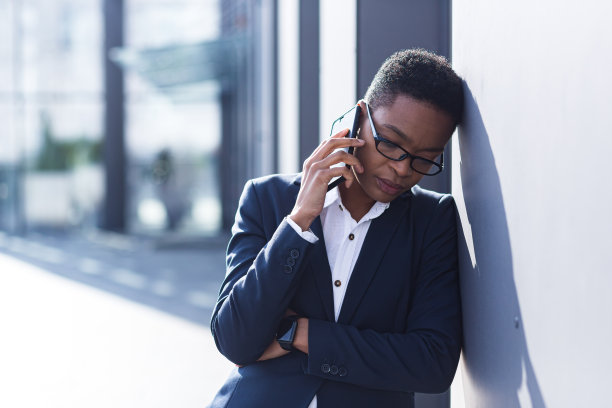 女商人伤心地在电话里抱怨，报告坏消息，非裔美国妇女绝望地在办公室附近，手拉着手放在脑后图片下载