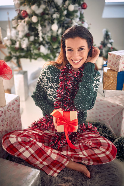 在一个美丽的节日早晨，在家里拿着圣诞礼物的女孩。图片下载