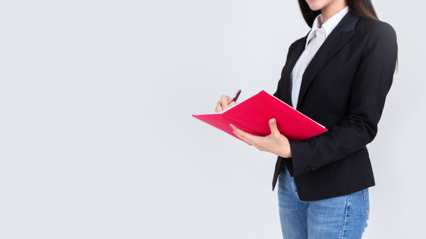 亚洲妇女穿着裤子牛仔裤写与钢笔笔记本上的白色背景。图片下载