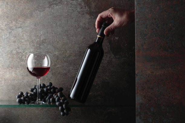 他伸手去拿一瓶红酒。图片下载