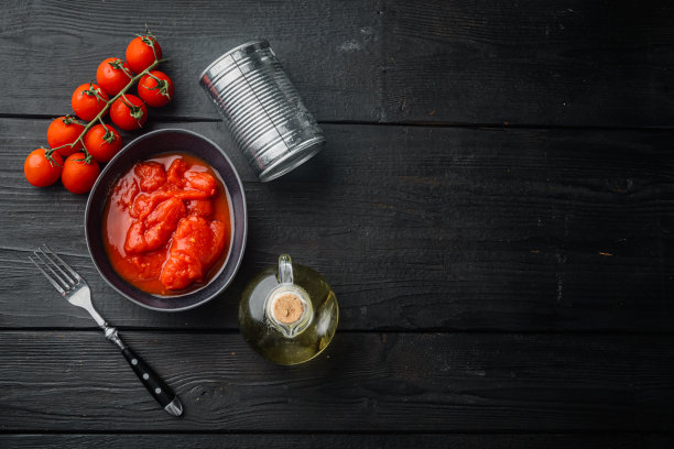 整罐番茄，在黑色木桌背景上，顶视图平放与文本复制空间图片下载