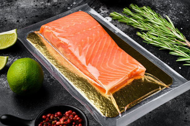 新鲜的生三文鱼牛排在真空包装，与香草，在黑色的石头桌子的背景图片下载