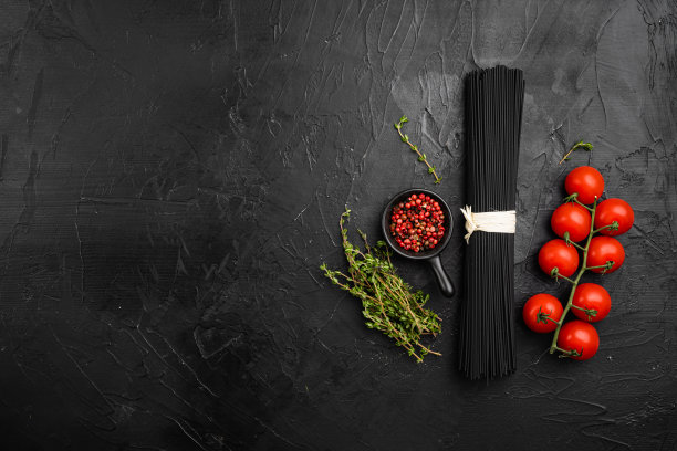 黑色的意大利面用墨鱼墨配食材，在黑石桌的背景上，顶视图平放，带文字复制空间图片下载