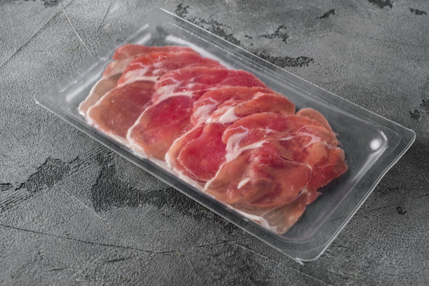 腌火腿火腿真空塑料包，在灰色的石头桌子的背景，为文本复制空间图片下载