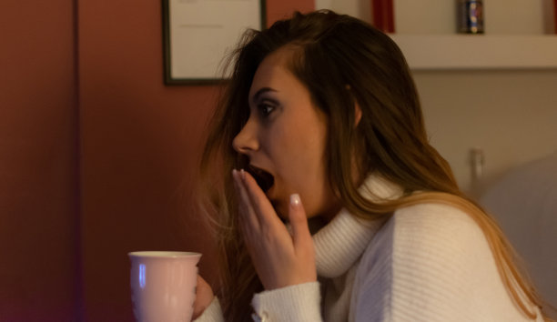 一个漂亮的年轻女人坐在家里的地板和沙发上，在黑暗中看电影，吃爆米花，微笑，享受她的空闲时间和周末活动的高清照片。图片下载