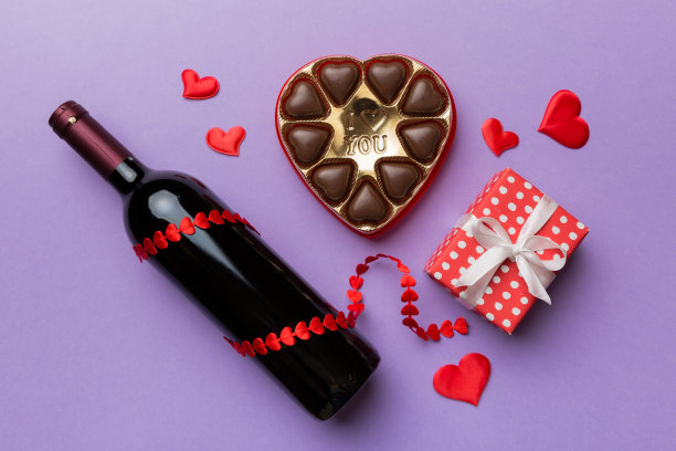 在彩色背景上的一瓶红酒，情人节的礼物和巧克力。心形巧克力礼品盒顶部视图与复制空间图片下载