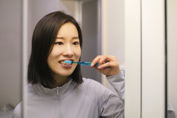年轻女子在镜子前刷牙图片下载