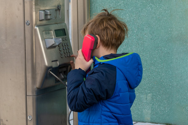 在公用电话里说话的男孩图片下载