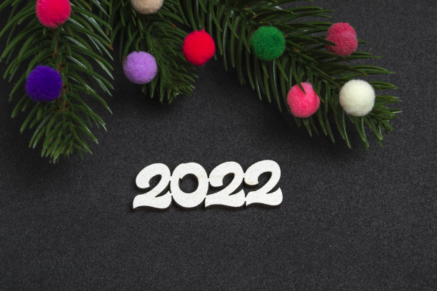 圣诞贺卡。弗拉特利圣诞树的树枝上有黑色背景上的彩色毛皮玩具，上面有2022的数字。图片下载