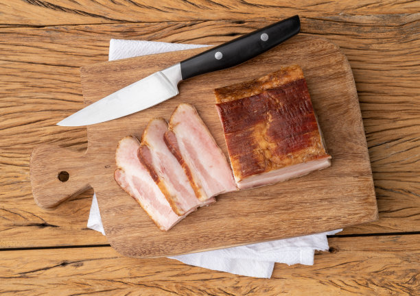 烟熏培根片和刀放在木板上图片下载