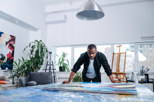 一个黑人站在一张桌子上放着油画的大画布旁边图片下载