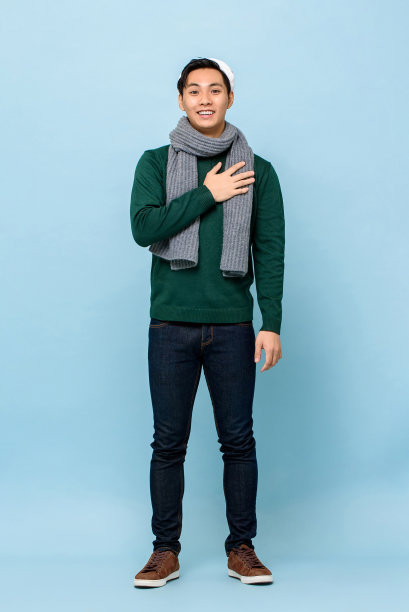 惊讶的年轻英俊的亚洲人在圣诞节服装触摸他的胸部在浅蓝色孤立的工作室背景图片下载