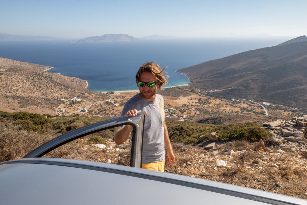 年轻人下车看全景，海滩风光自驾游的概念图片下载
