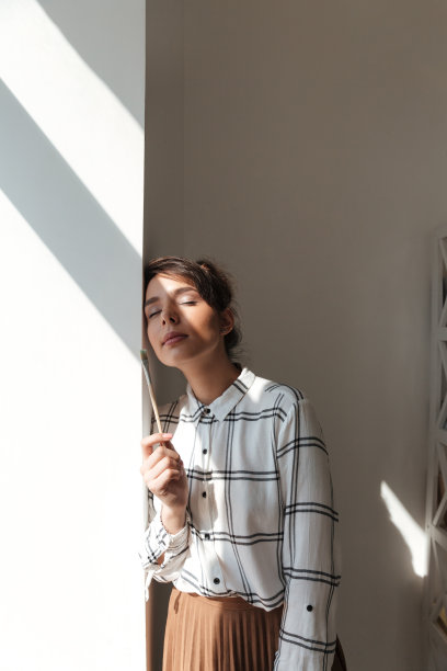 一个微笑的女艺术家的肖像拿着画笔和摆姿势图片下载