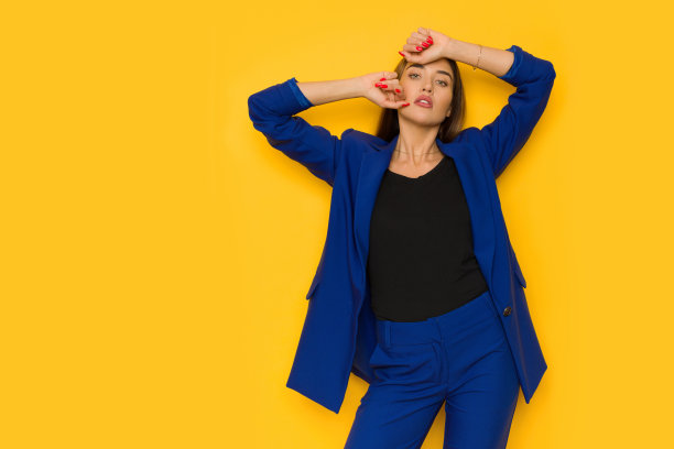 年轻女子穿着优雅的特大号海军蓝夹克，双手捧着头摆姿势。图片下载