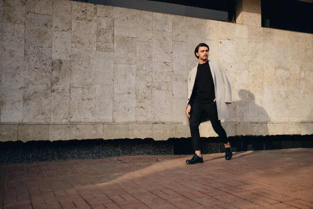 穿着外套的年轻英俊时髦的男人若有所思地看向别处，走在户外图片下载