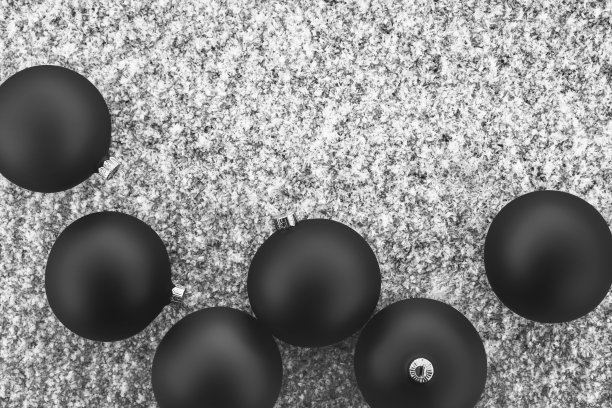 黑色圣诞球在新雪上。灰色圣诞背景。圣诞快乐，恭贺新禧。顶视图，平铺，复制空间。图片下载