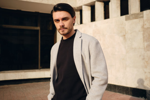 年轻英俊时髦的男人在外套专心地看着摄像机在室外图片下载