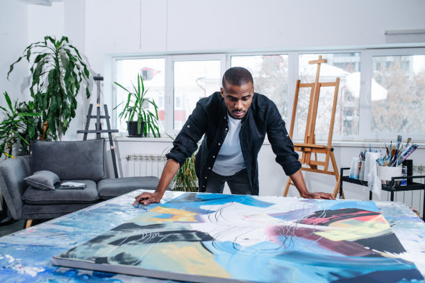 一个善于观察的黑人站在一张桌子上放着油画的大画布旁边图片下载