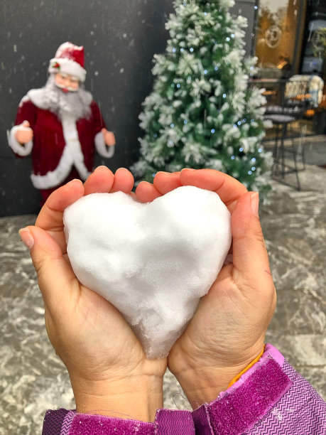 一个女孩手中用雪做成的心形圣诞装饰品图片下载