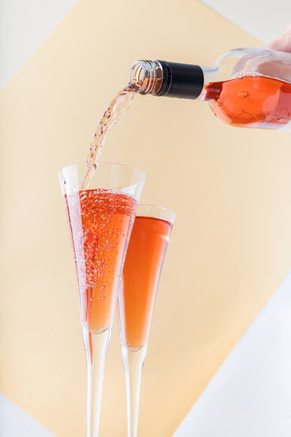 玫瑰葡萄酒倒在米色背景的玻璃杯上图片下载