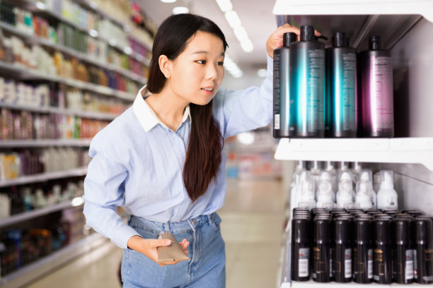年轻的亚洲女人在超市挑选洗发水的肖像图片下载